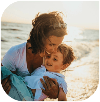 Mother and son enjoying a joyful moment on the beach at sunset.