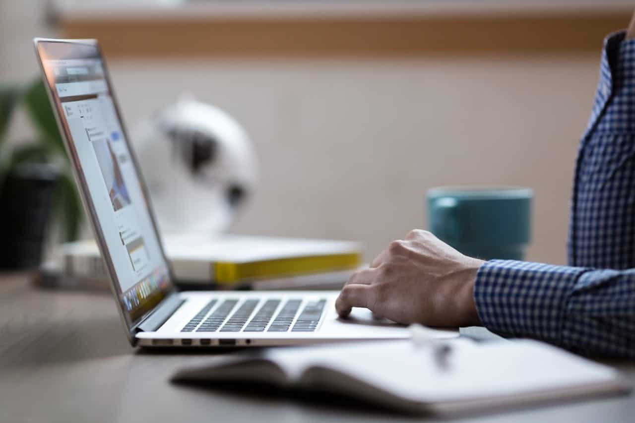 Laptop user working at a desk with a cup and documents.