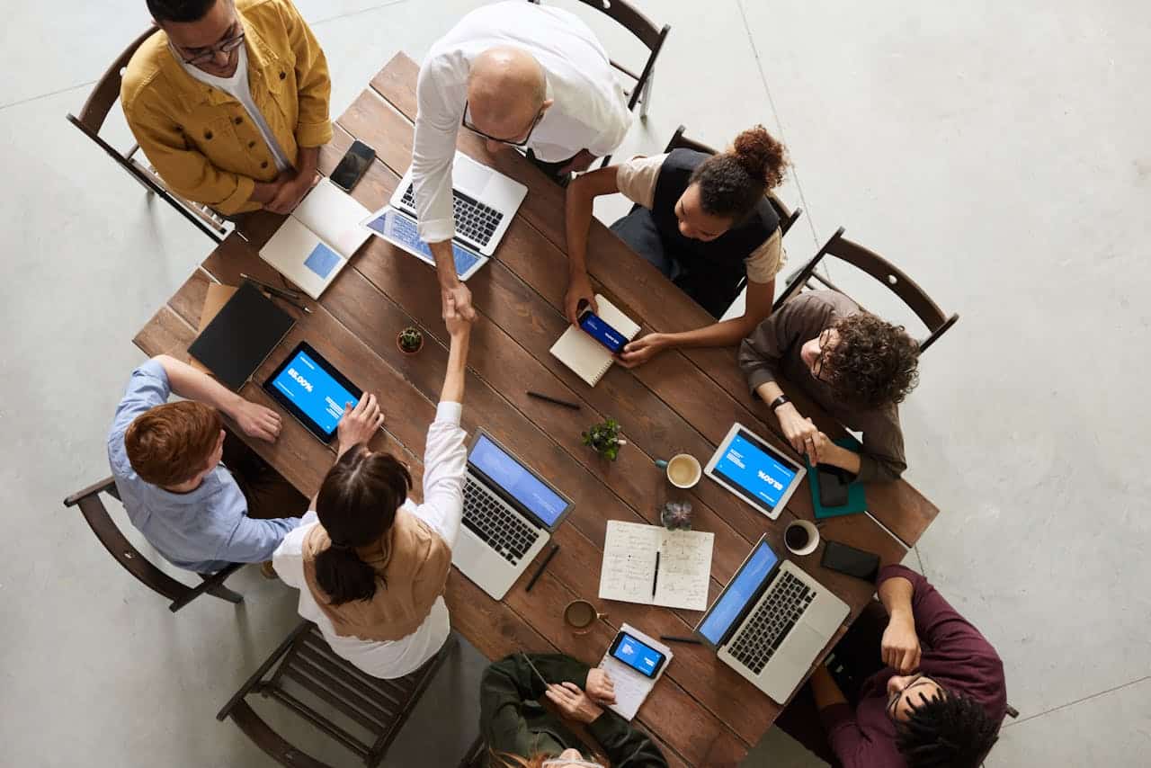 Team collaboration meeting with diverse professionals using laptops and tablets.