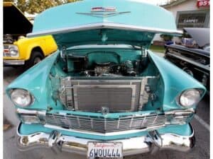 Vintage turquoise classic car with open hood showing engine.